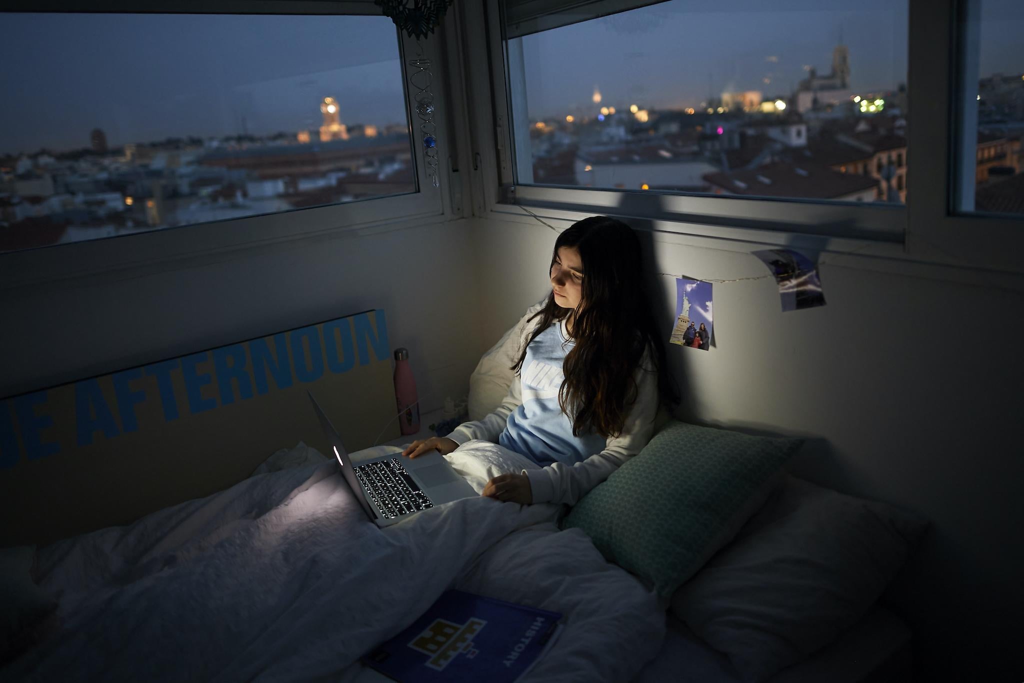 In this photo illustration, a teenage girl watches a series on the bed in her room on March 18, 2020 in Madrid, Spain