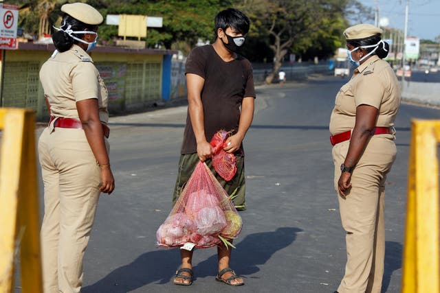 A man carrying vegetables is stopped by police at a barricade on a road on Wednesday in Chennai, India