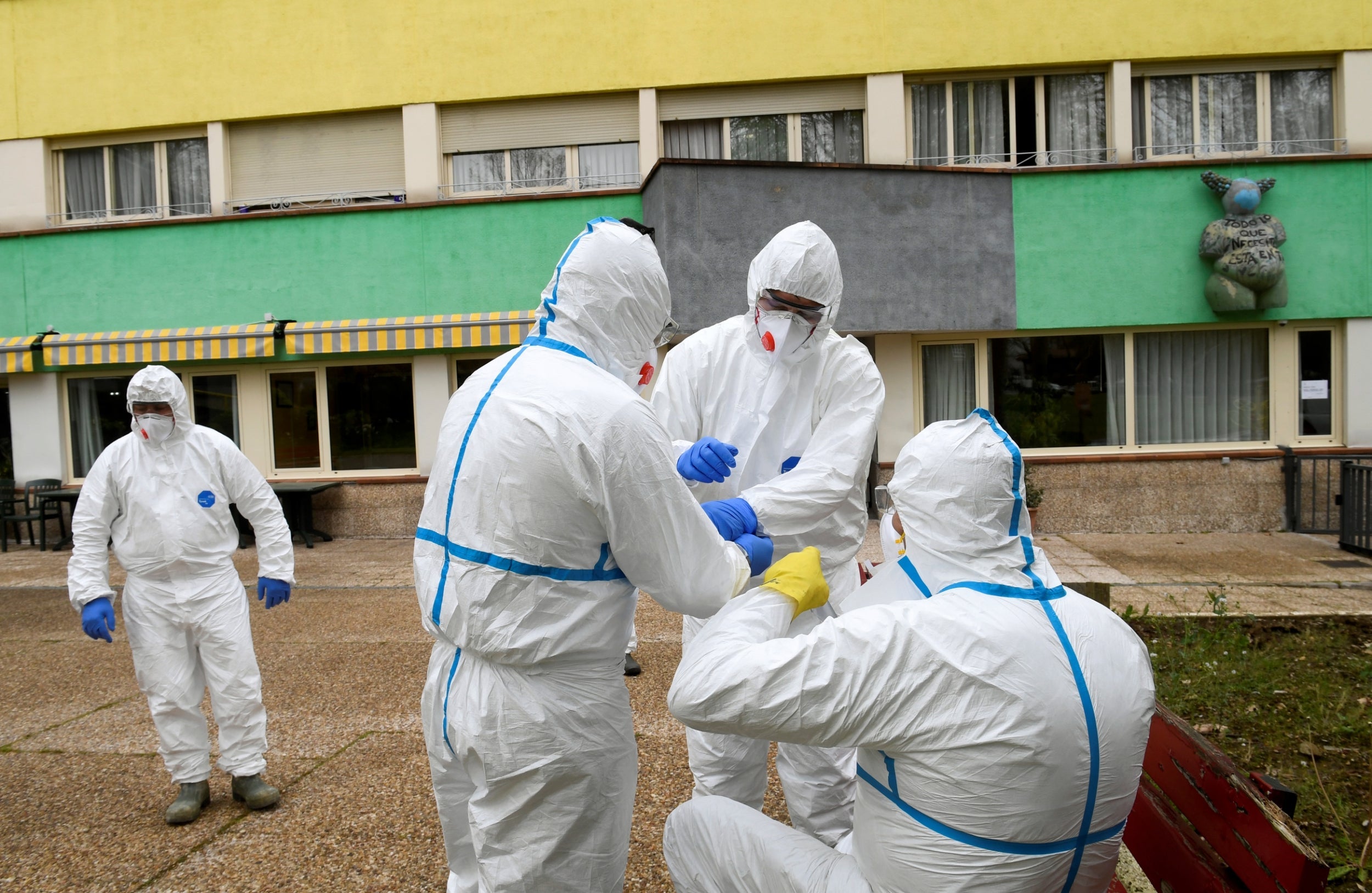 Workers prepare to clean the nursing home where a woman died and several residents and care providers have been diagnosed with coronavirus in Grado, Asturias