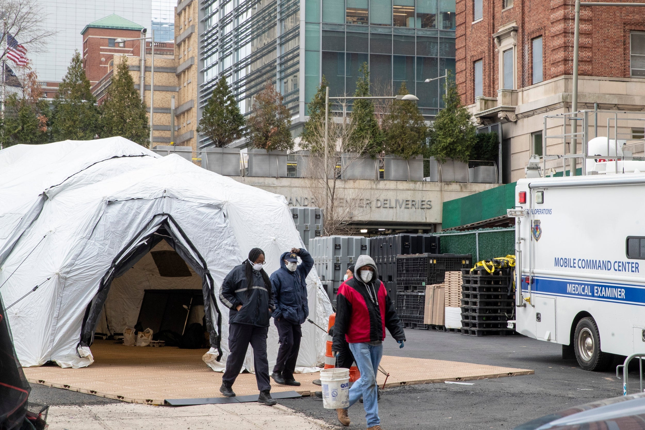 Medical Examiner personnel and construction workers are seen at the site of a makeshift morgue being built in New York, Wednesday, March 25, 2020.