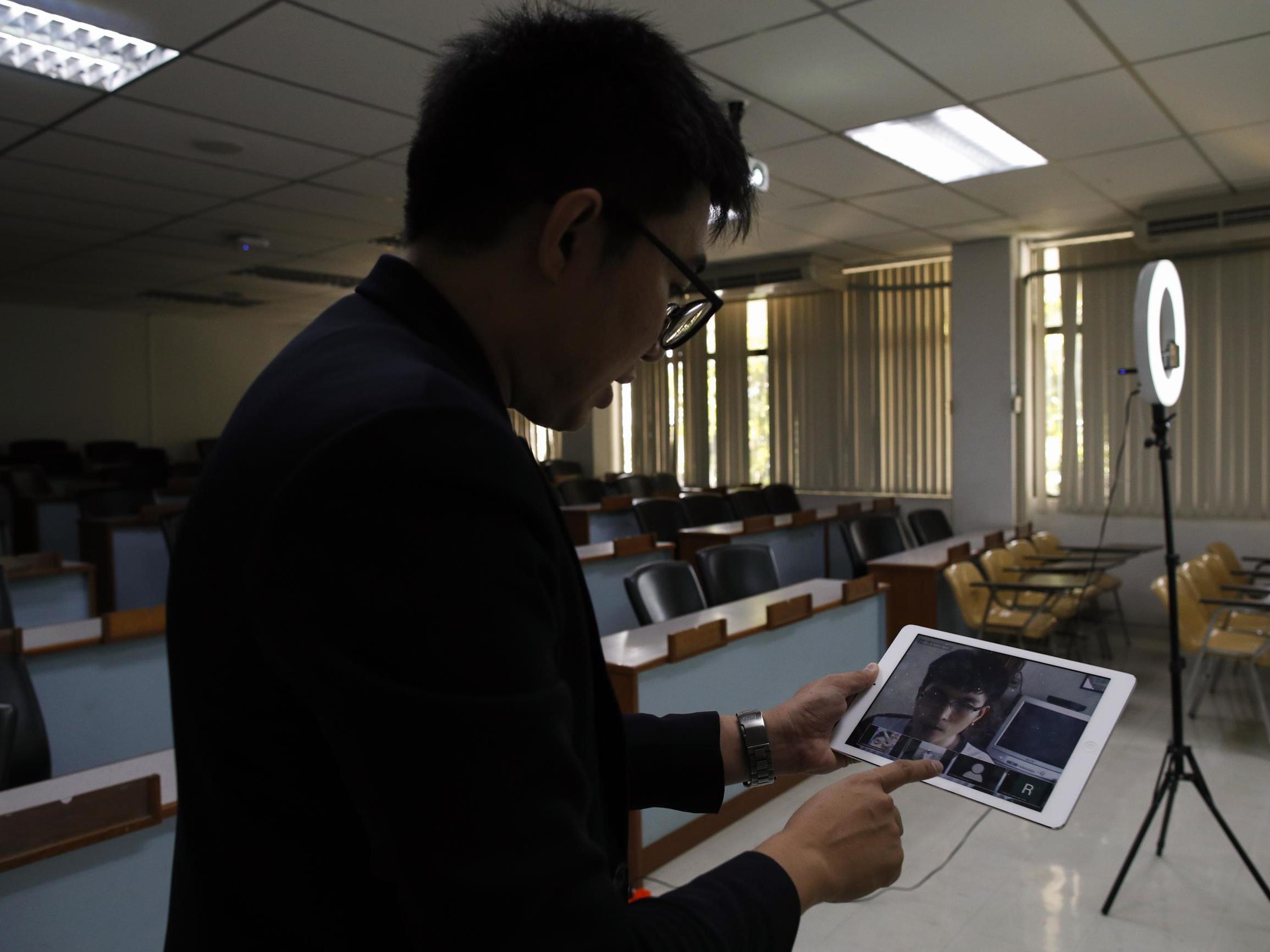 A lecturer speaks to students via a video-conference app in Thailand