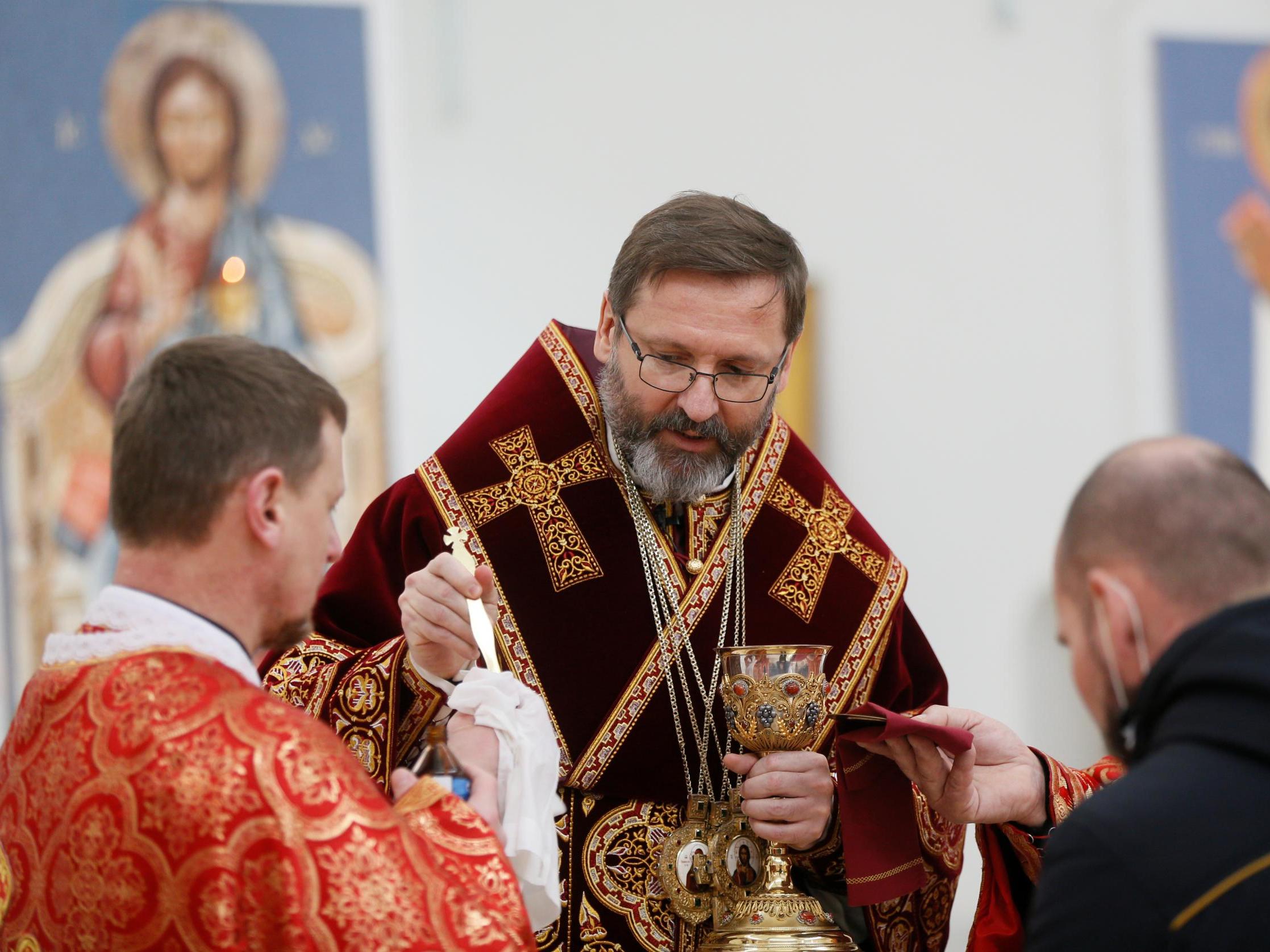 An archbishop disinfects the holy spoon for communion during a service in Kiev, Ukraine