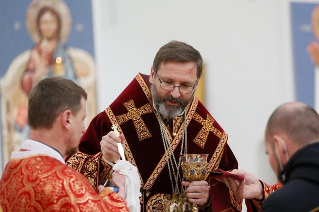 An archbishop disinfects the holy spoon for communion during a service in Kiev, Ukraine
