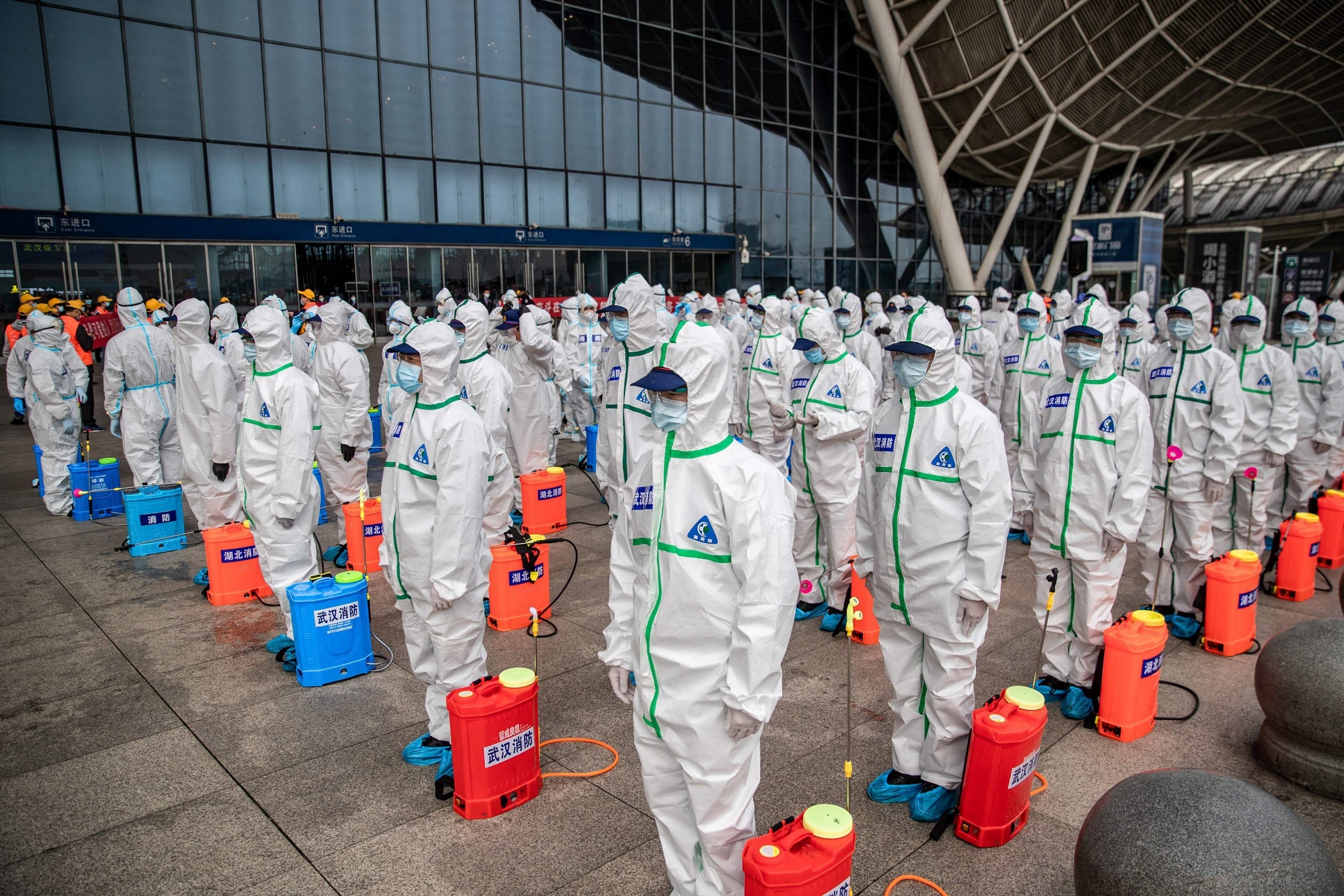 Staff members line up at attention as they prepare to spray disinfectant at Wuhan Railway Station
