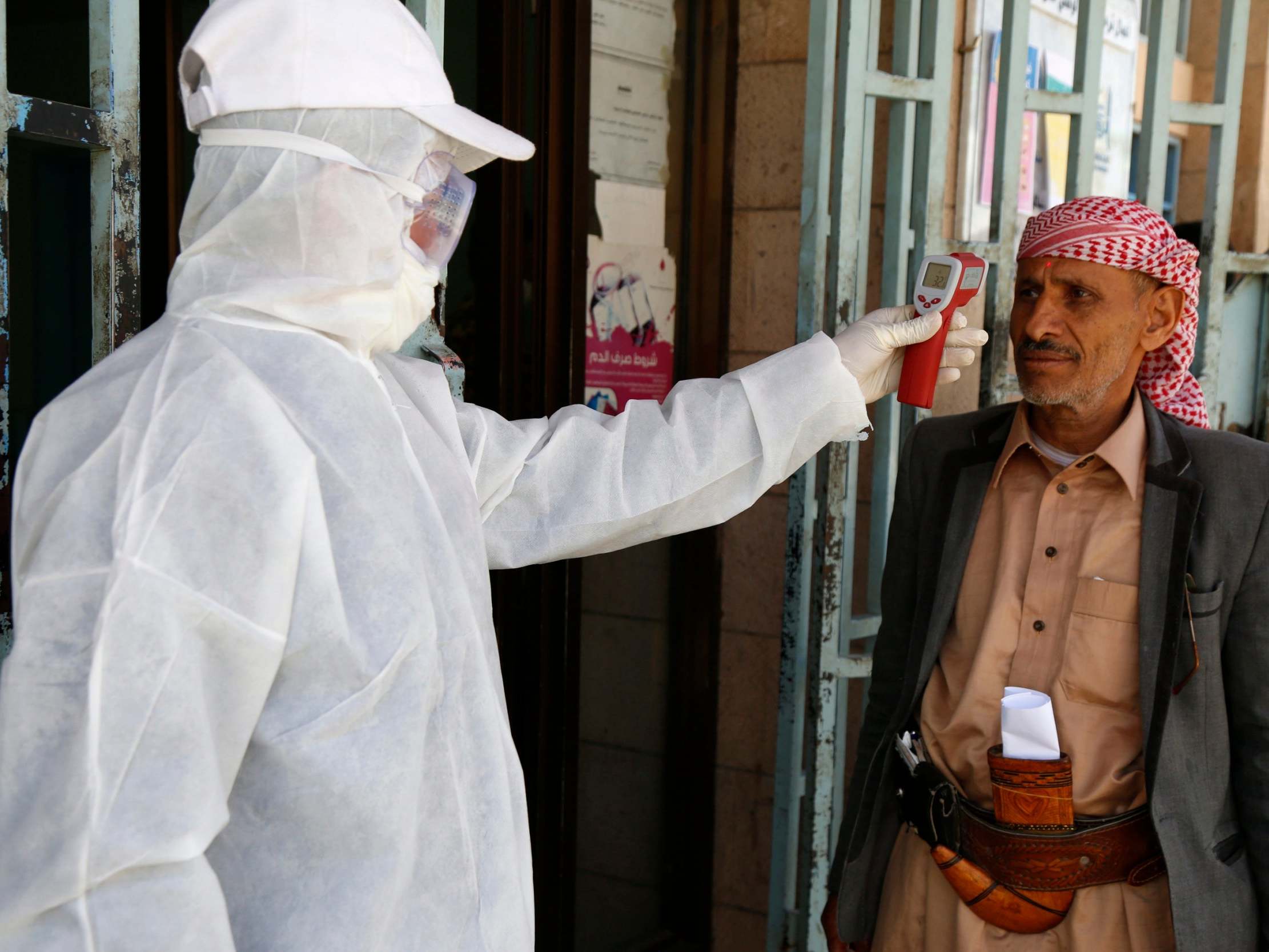 A medical worker measures the body temperature of a man at a state-run facility as a precautionary measure to combat Covid-19 on 24 March 2020 in Sana'a, Yemen.