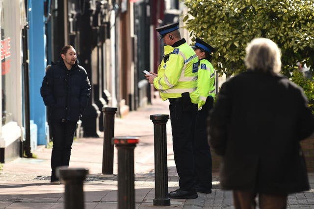 Police community support officers talk to a man on a street in Brighton, southern England on March 24, 2020 after the British government ordered a lockdown to help stop the spread of coronavirus