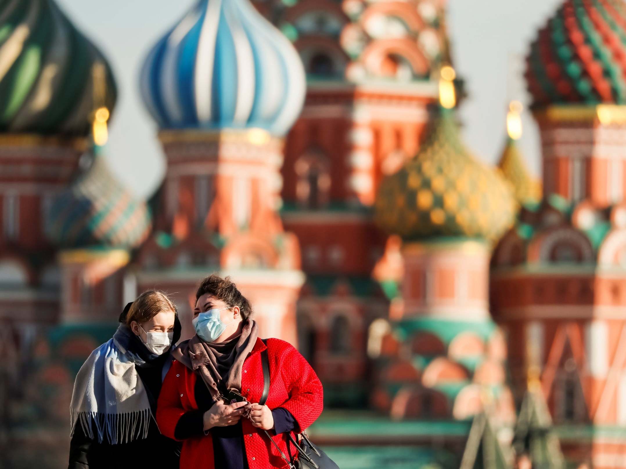 Women with protective masks walk across Red Square in Moscow