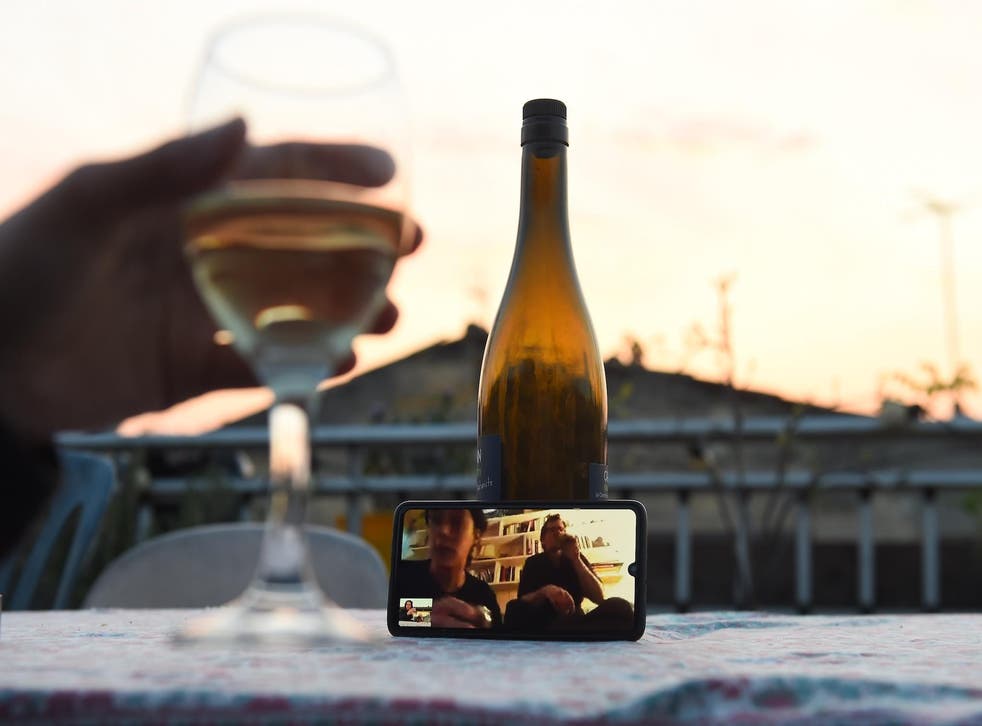 A woman drinks a glass of wine as she speaks and shares a drink with friends via a video call on March 26, 2020, in Bordeaux, southwestern France