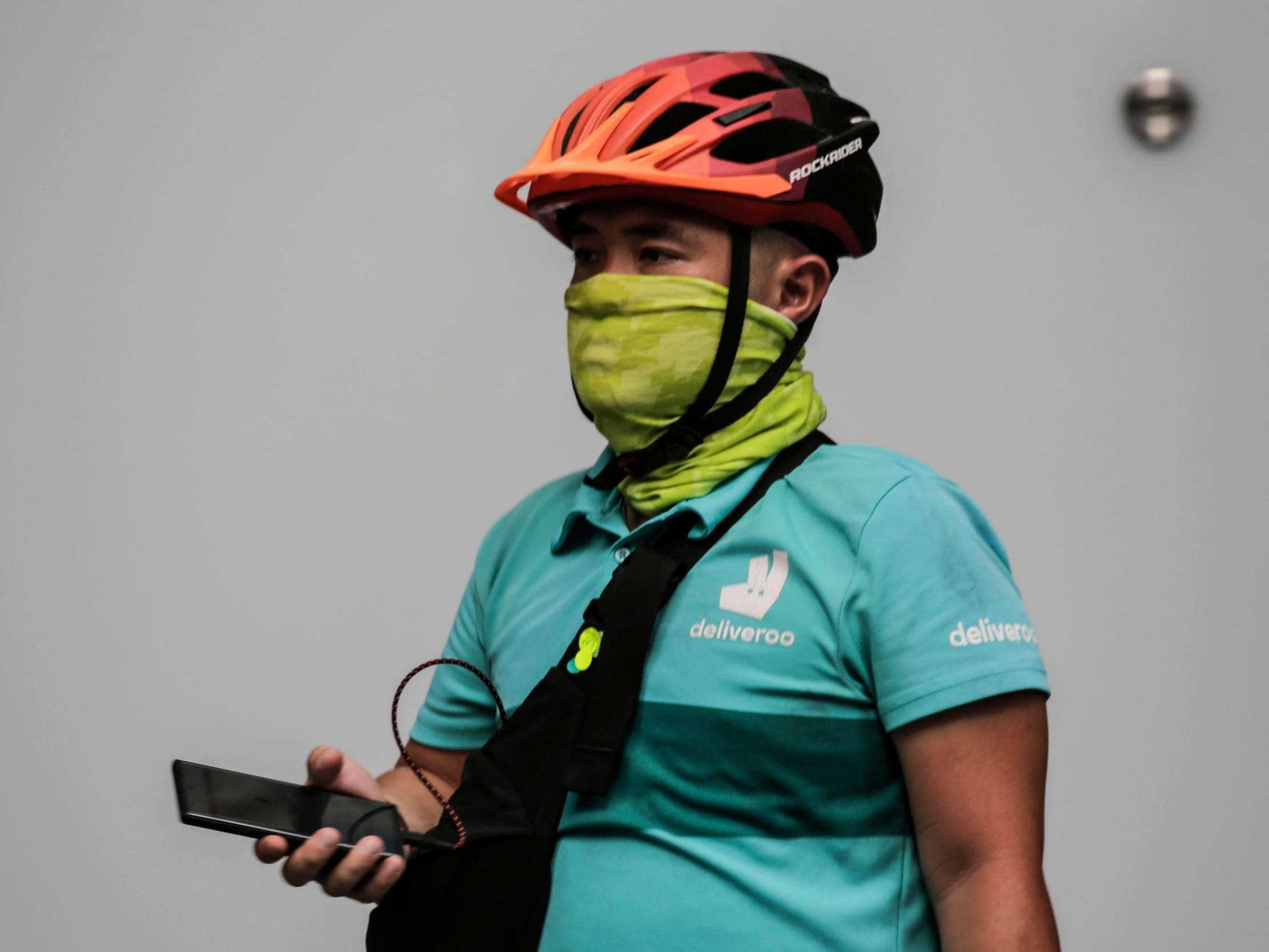 A Deliveroo food delivery rider with his mouth and nose covered walks through the financial district of Singapore on 26 March 2020.