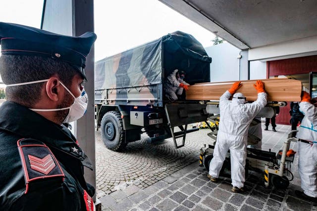 Italian soldiers wearing protective suits transport coffins onto military trucks, 27 March 2020