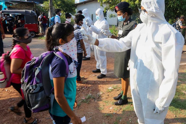 Sri Lanka Army personnel check the body temperature of stranded employees before transporting them home from the Biyagama Free Trade Zone in the suburbs of Colombo, Sri Lanka, 28 March 2020.
