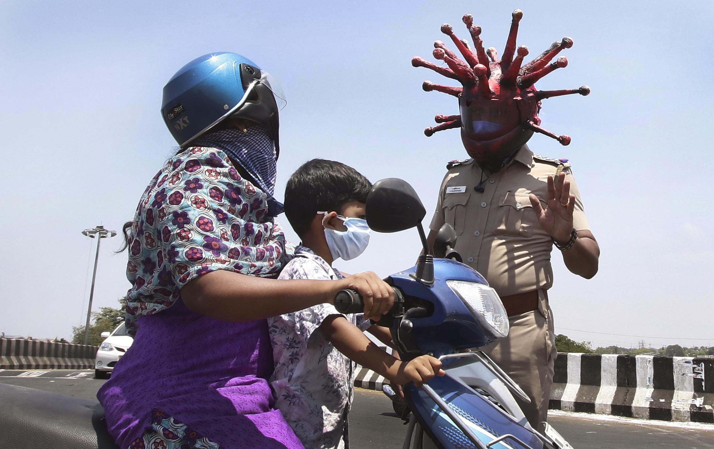 Police officer Rajesh Babu wears a helmet representing the coronavirus, and requests commuters to stay home during the 21-day countrywide lockdown that began Wednesday in Chennai, India