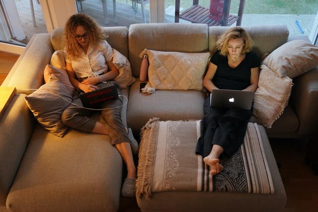 A mother, who is temporarily working from home, and her daughter, home after her university was temporarily closed, sit on a couch at their laptop computers at their home during the coronavirus crisis on March 28 in Berlin, Germany