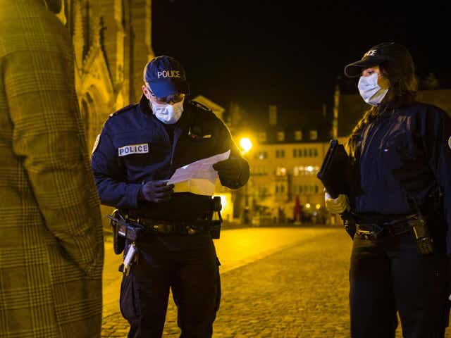 French police check a mobility form required by citizens to go outside of their homes, in an effort to stem the spread of coronavirus
