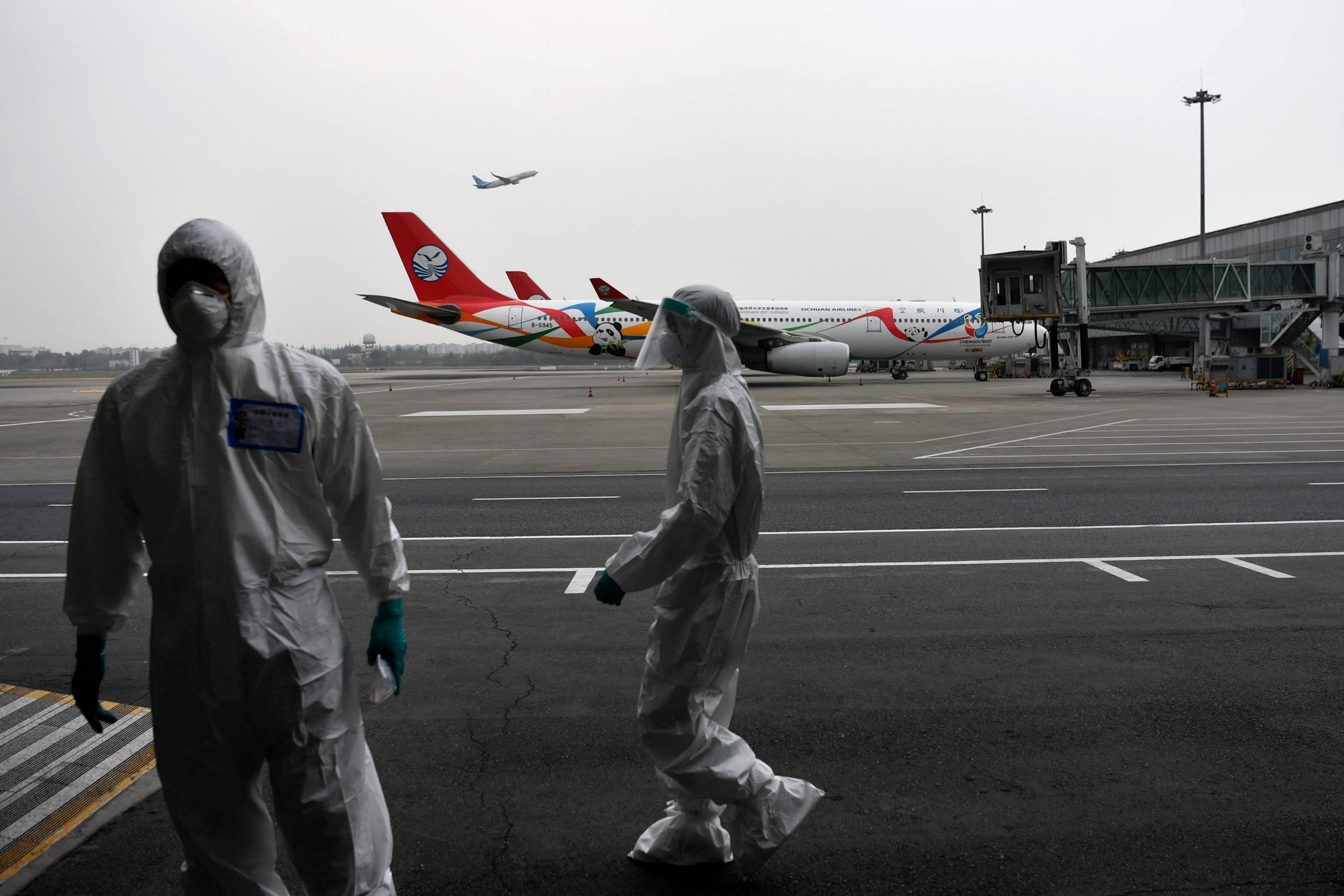 Customs officers in protective suits on the tarmac at Chengdu Shuangliu International Airport