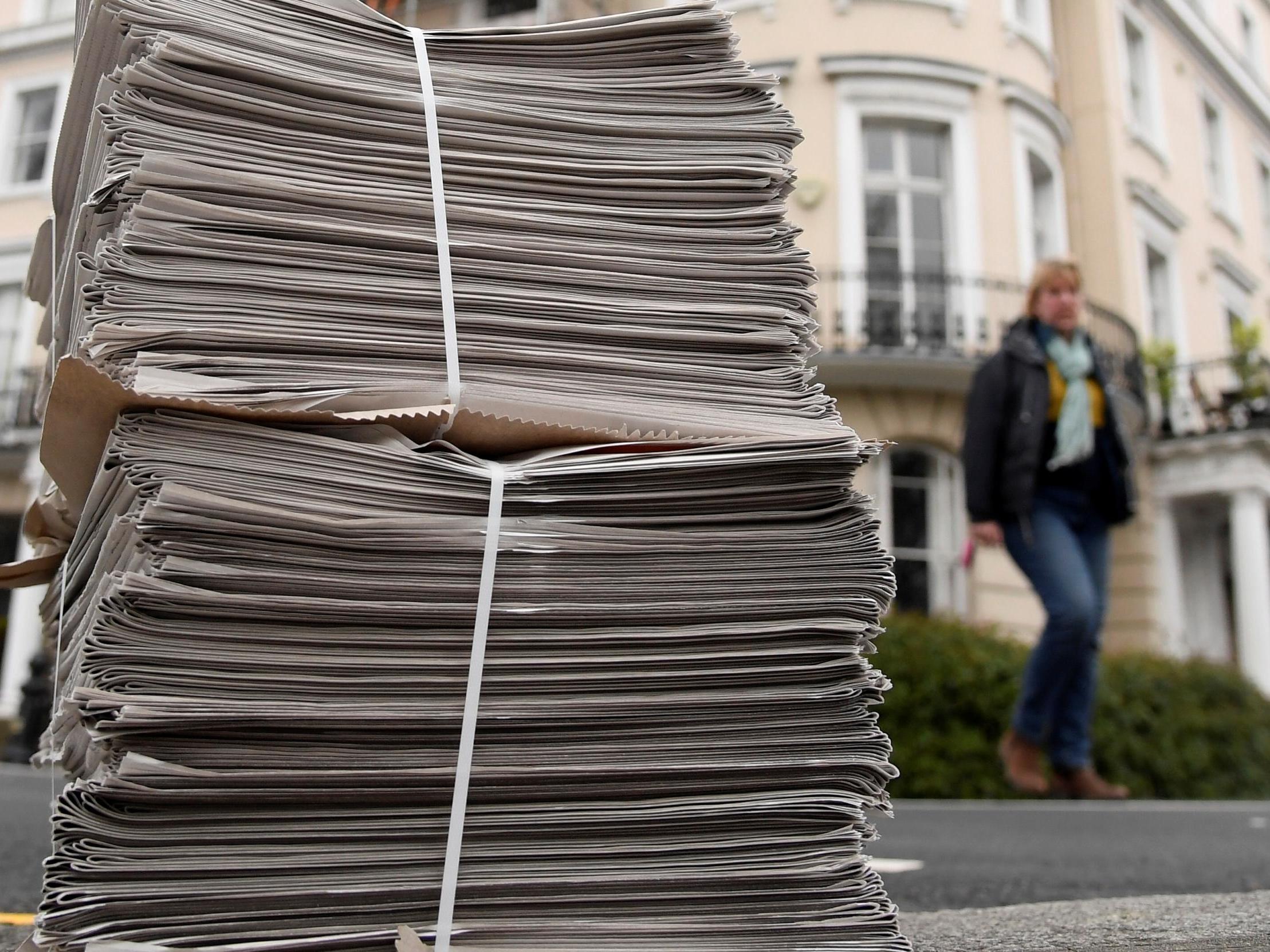 A pile of newspapers are seen on a pavement awaiting delivery to homes in London as the spread of the coronavirus continues