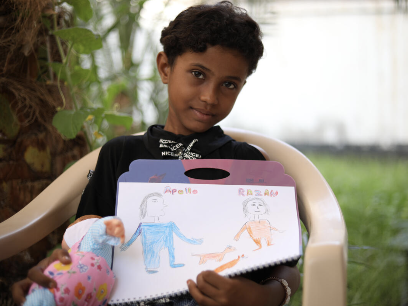 Razan* holds a drawing of her and her friend Apollo (Save The Children)