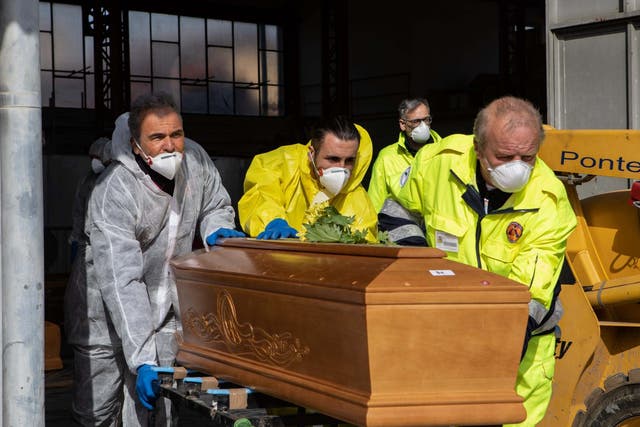 Carabinieri officers, wearing protective suits, transport coffins on 28 March 2020 in Ponte San Pietro, near Bergamo, Northern Italy.