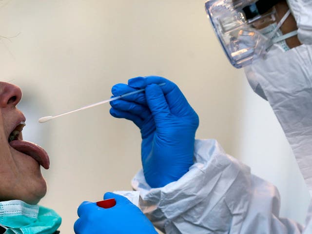 Medical staff in a mobile unit take samples from a woman to test for Covid-19