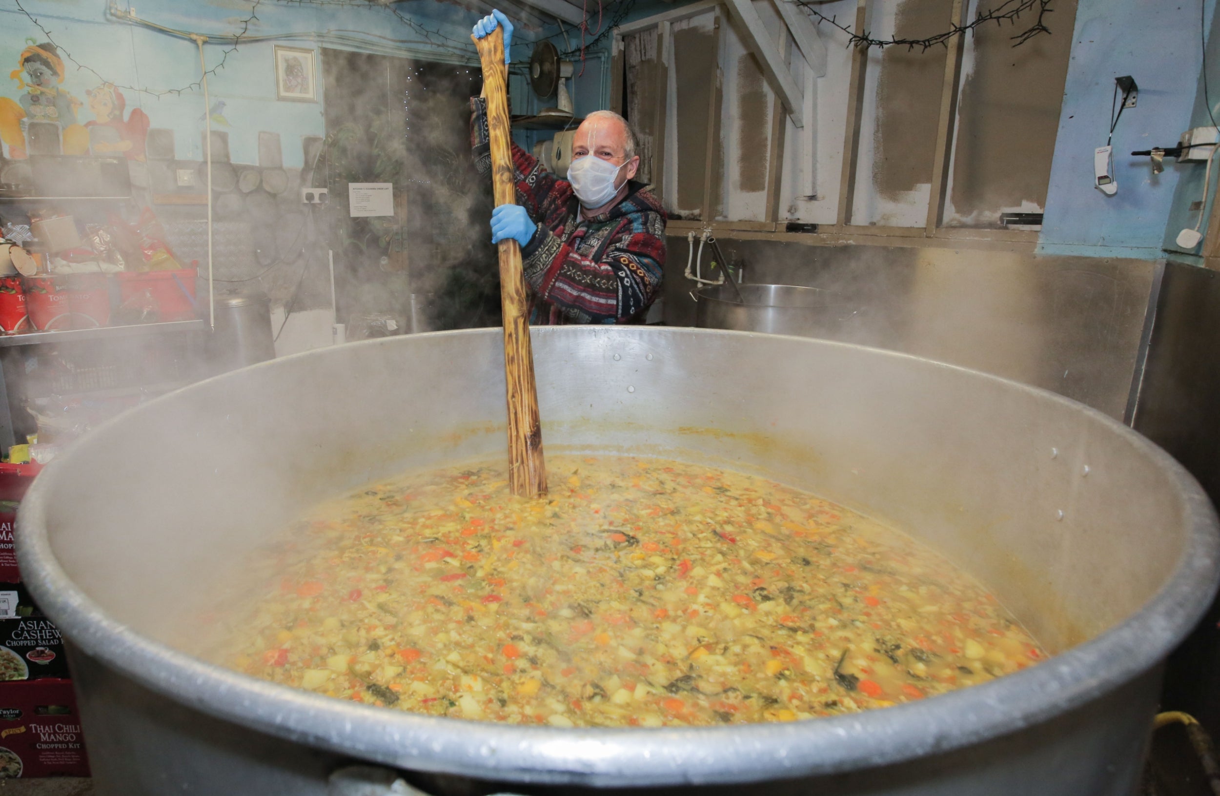 Cooking For Haringey with Para stirring the giant cooking pot containing a vegetable curry dish with a boating oar at their headquarters in the City of London