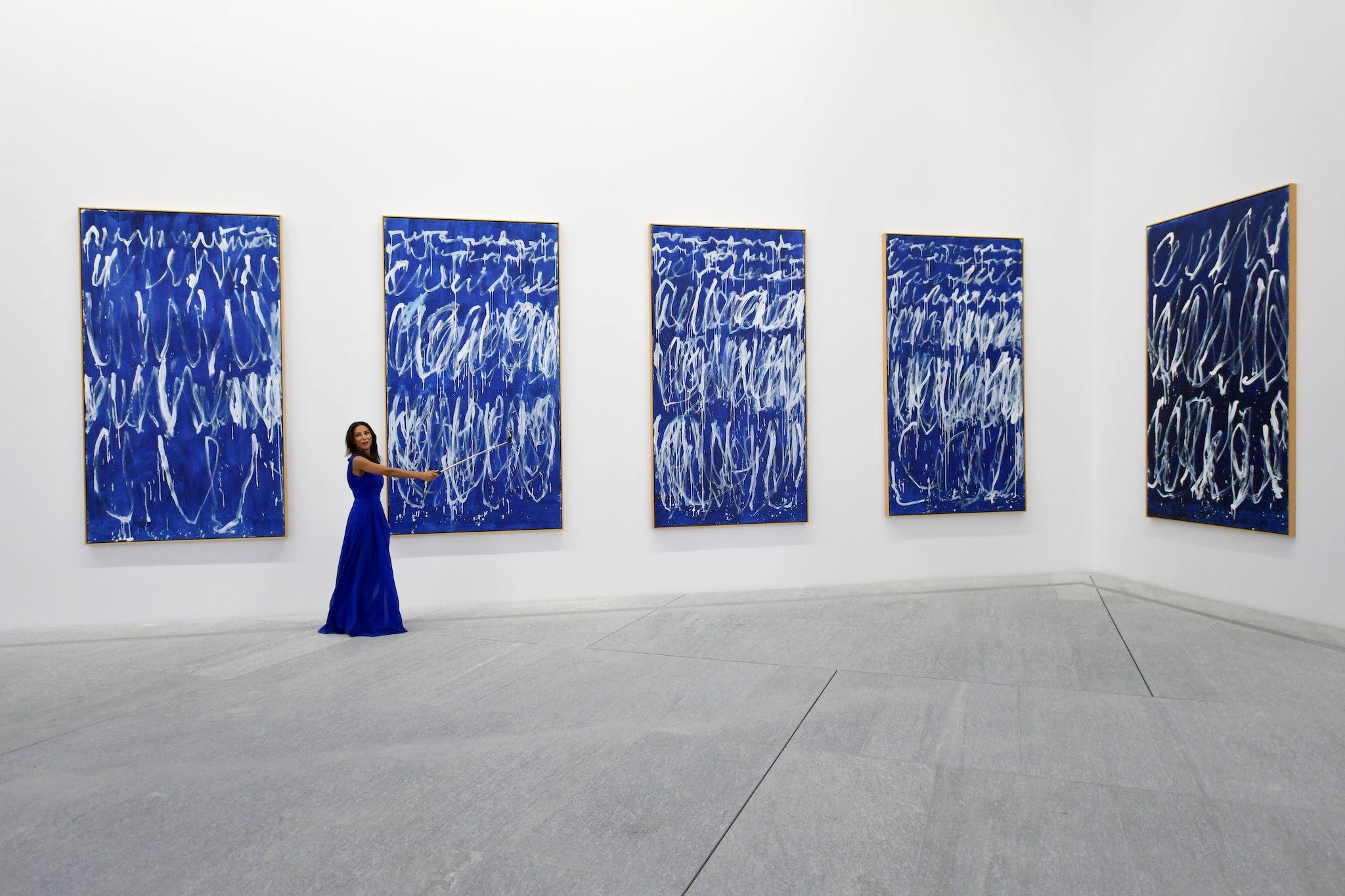 A woman takes a selfie in front of part of a series of nine panels titled "Untitled I-IX" by American painter Cy Twembly