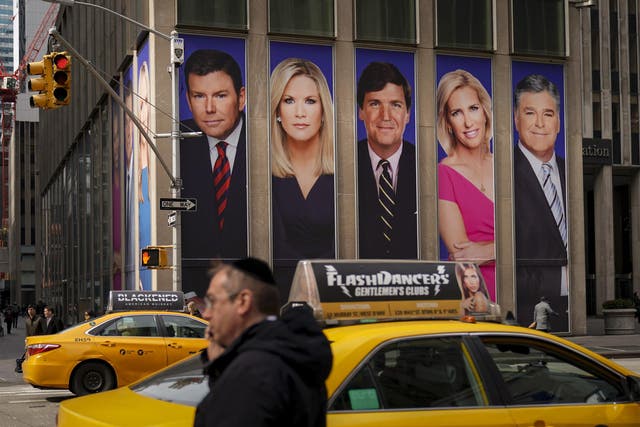 Traffic on Sixth Avenue passes by advertisements featuring Fox News personalities, including Bret Baier, Martha MacCallum, Tucker Carlson, Laura Ingraham, and Sean Hannity.