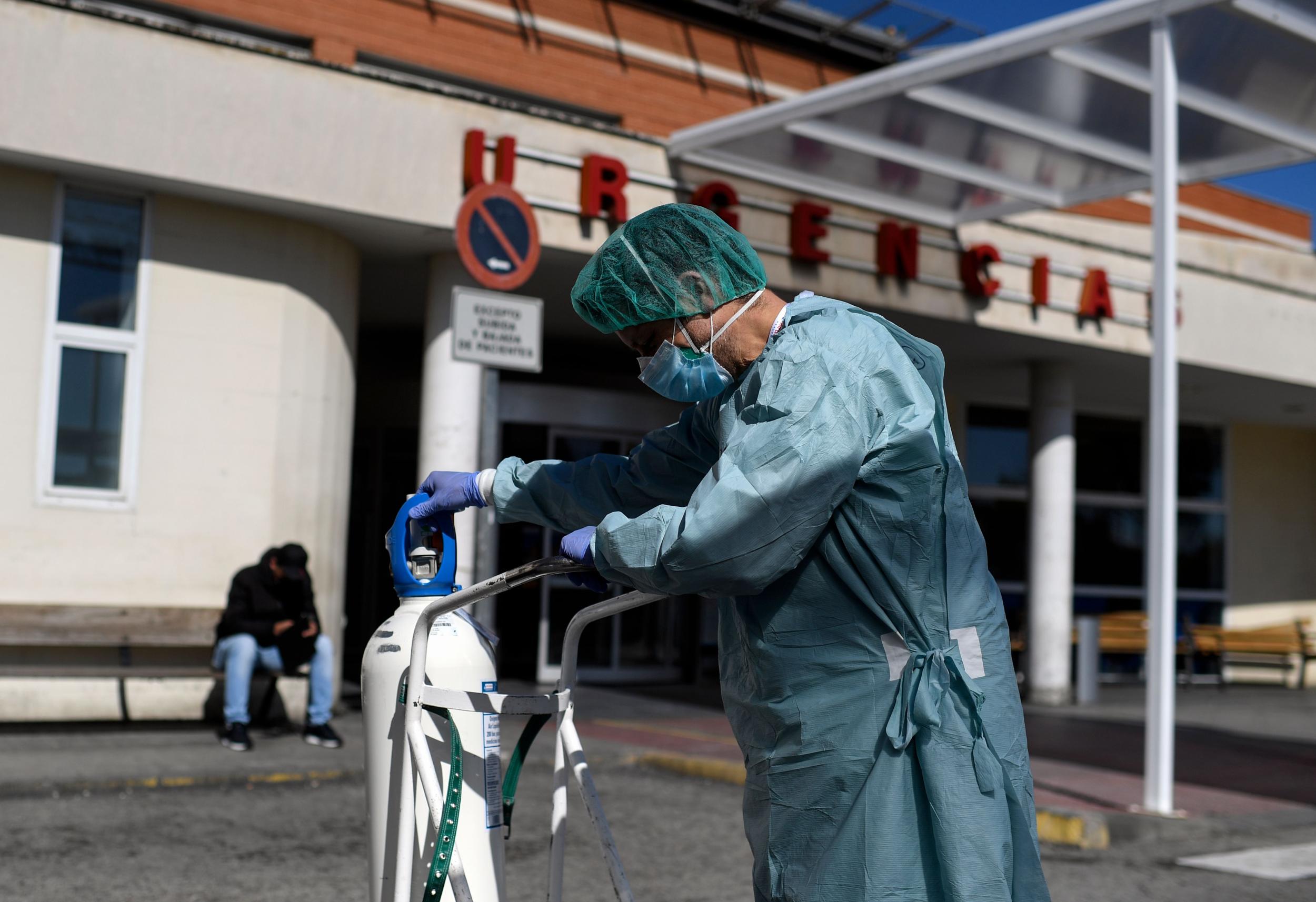 A healthcare worker holds a oxygen bottle outside the 12 Octubre Hospital in Madrid