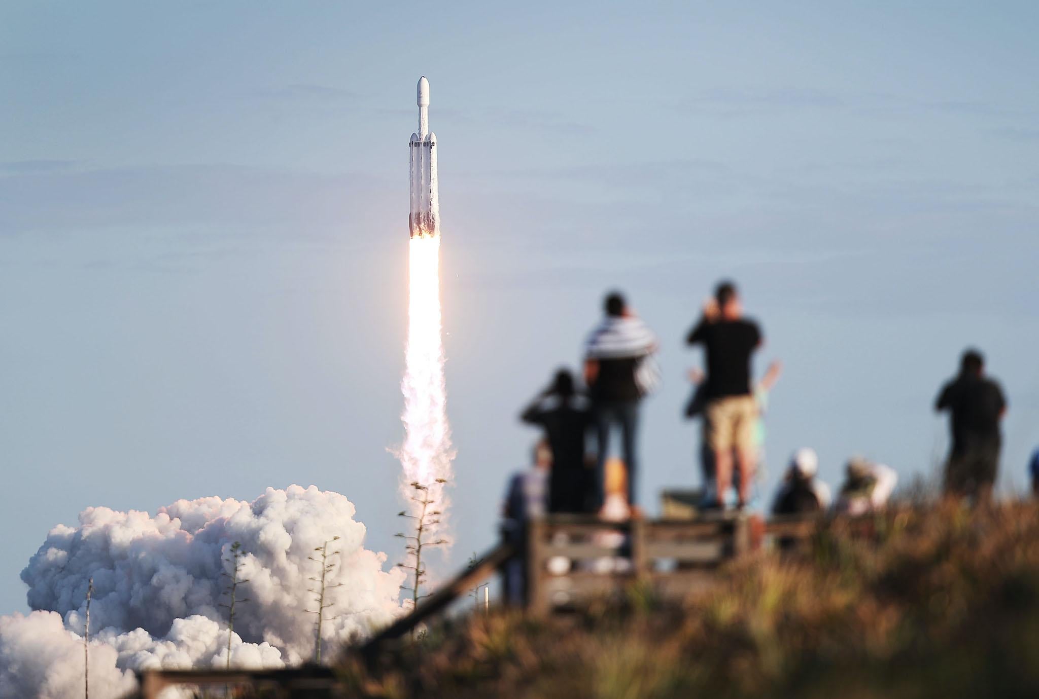 People watch as the SpaceX Falcon Heavy rocket lifts off from launch pad 39A at NASA's Kennedy Space Center