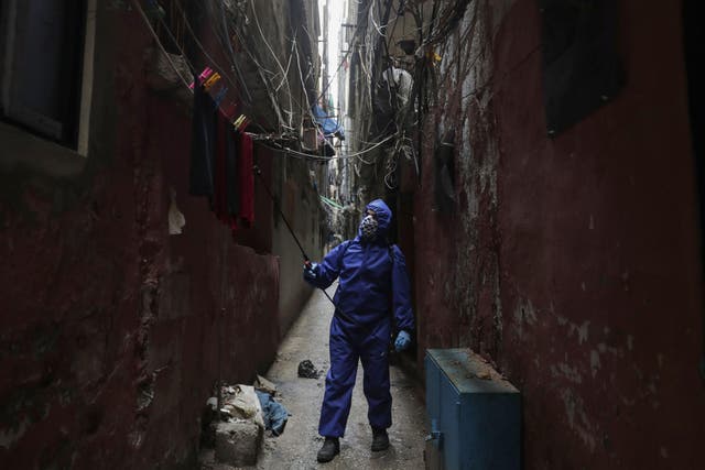 A volunteer with Palestinian associations sprays disinfectant in narrow streets at the Shatila camp for Palestinian refugees