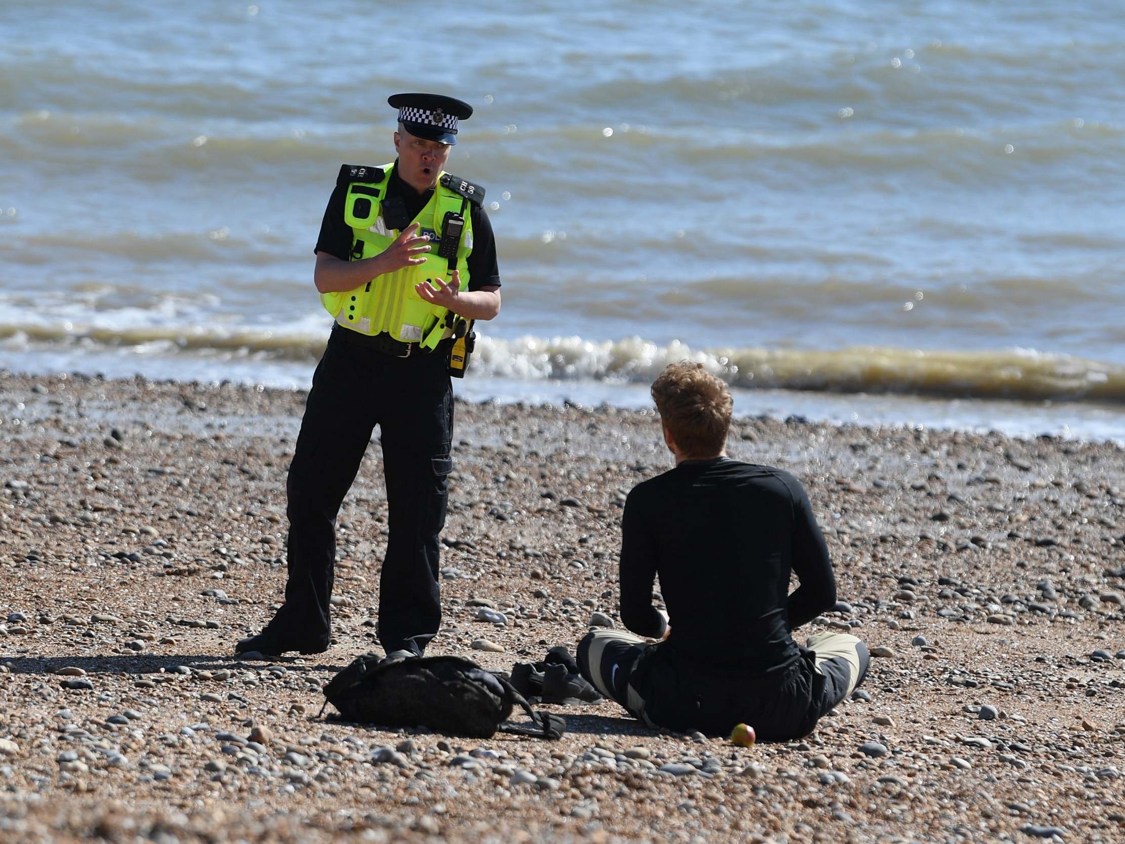 A police officer moves a member of the public off Brighton beach on April 04, 2020