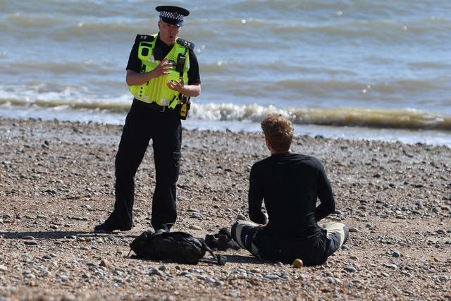 A police officer moves a member of the public off Brighton beach on April 04, 2020