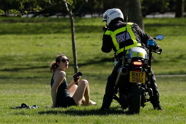 A police officer advises a woman to go home after spotting her enjoying the sun in Primrose Hill, London