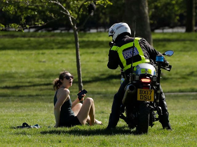 A police officer advises a woman to go home after spotting her enjoying the sun in Primrose Hill, London