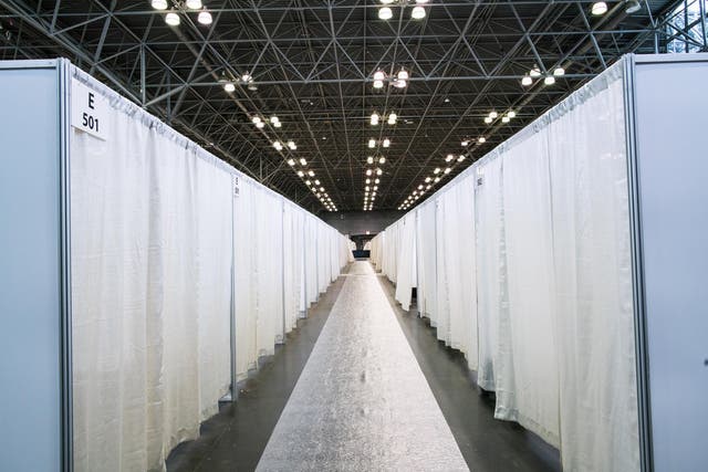 <p>A row of hospital bed booths are seen at the Jacob K Javits Convention Center</p>