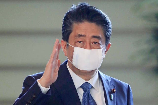 Japanese Prime Minister Shinzo Abe gestures as he arrives at the prime minister's official residence in Tokyo