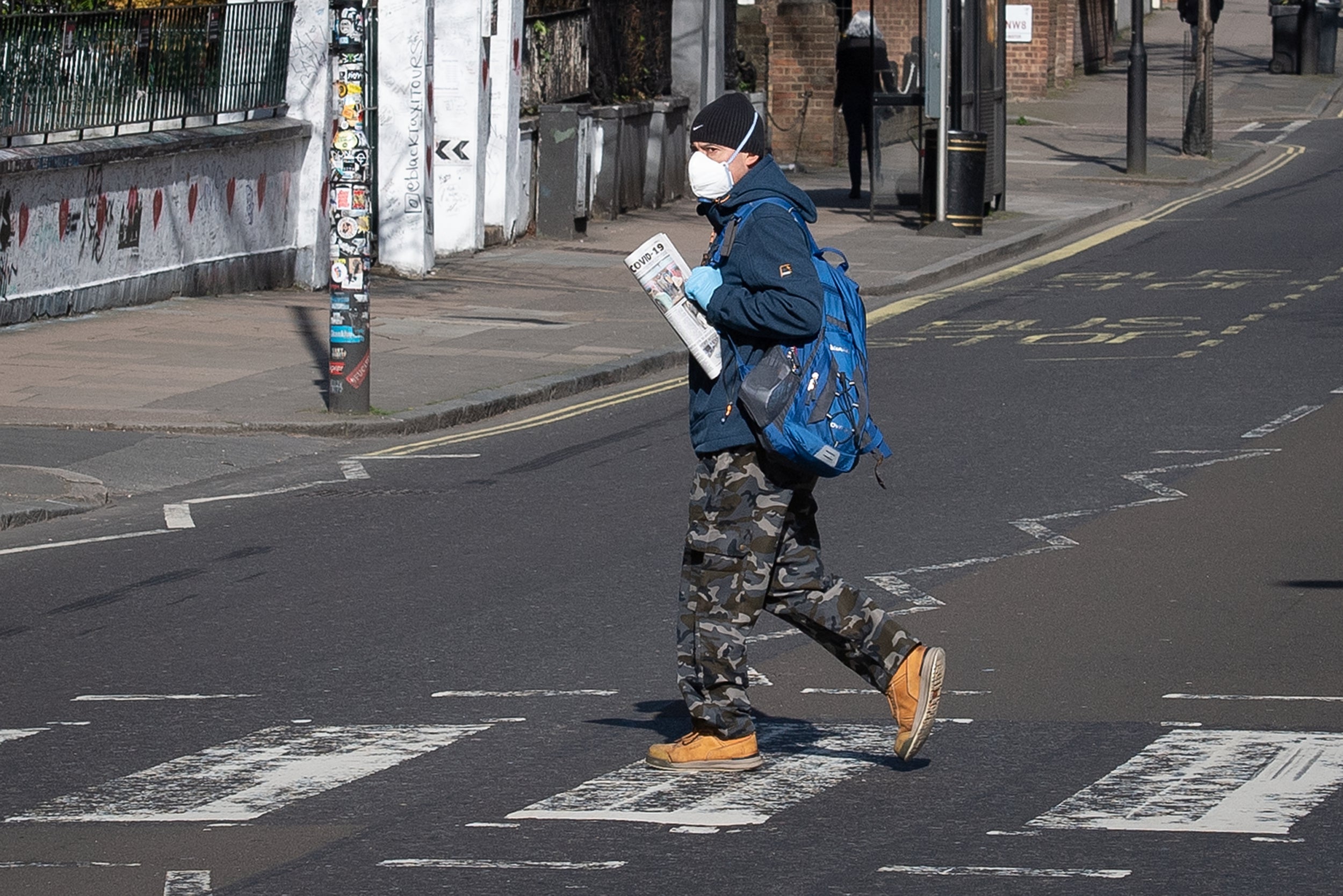 A member of the public wearing a protective mask walks on the Abbey Road pedestrian crossing