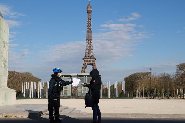 A French police officer does a check on a person near the Eiffel Tower during the country's lockdown over its coronavirus outbreak