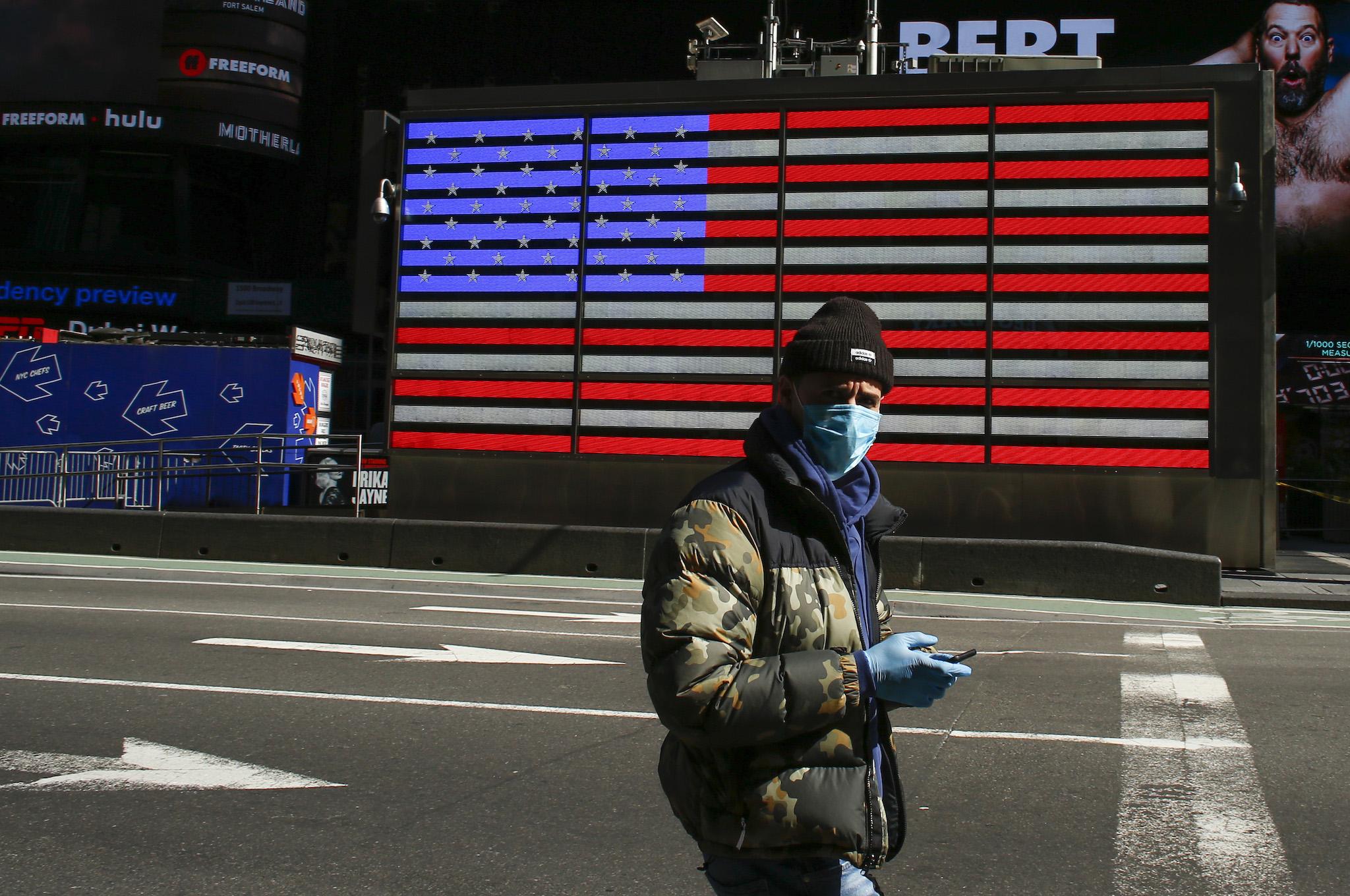A man wears a face mask as he check his phone in Times Square on March 22, 2020 in New York City