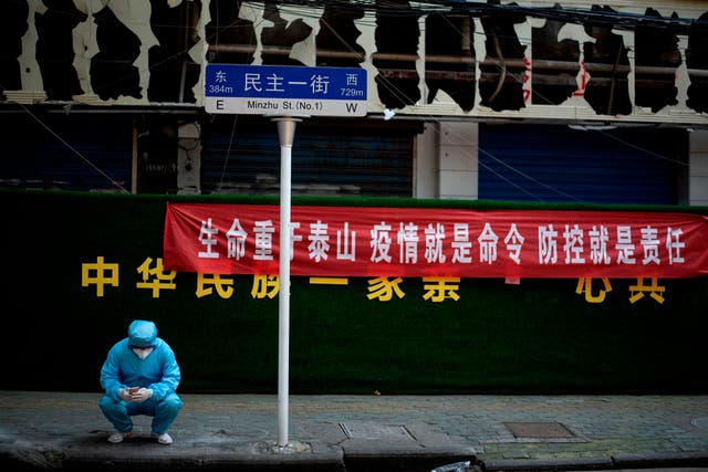 A man wearing personal protective gear uses his phone in Wuhan on Tuesday