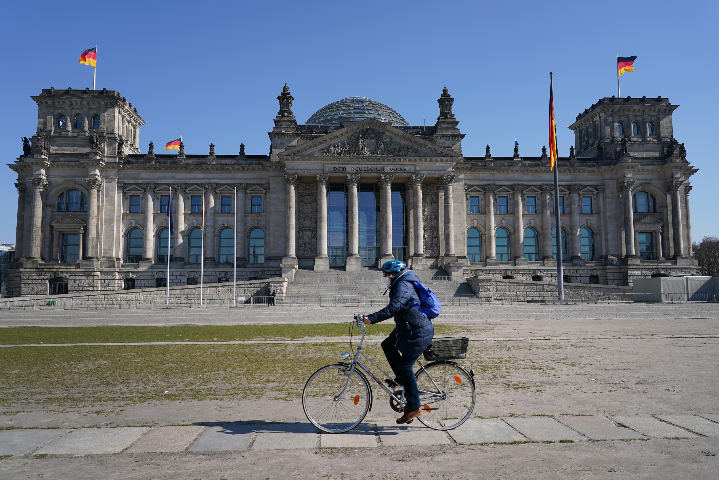A woman rides a bicycle past the Reichstag, Berlin