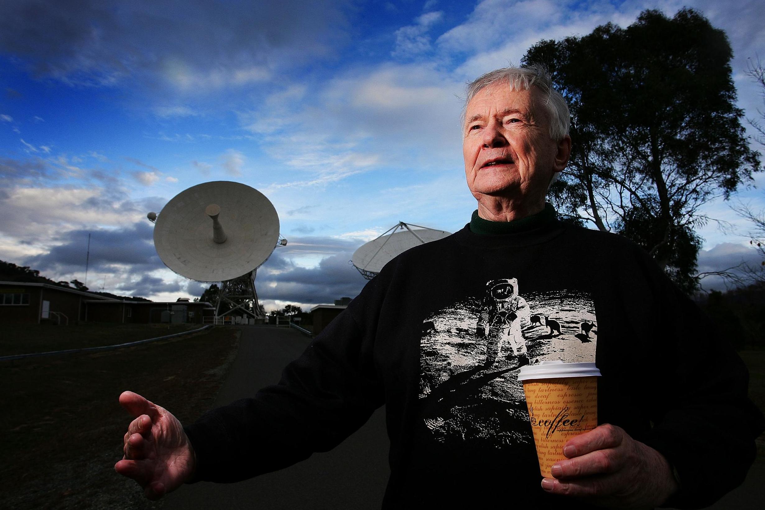 Honeysuckle Creek operations supervisor John Saxon; the DSS-46 antenna of the Canberra Deep Space Communication Complex can be seen behind him