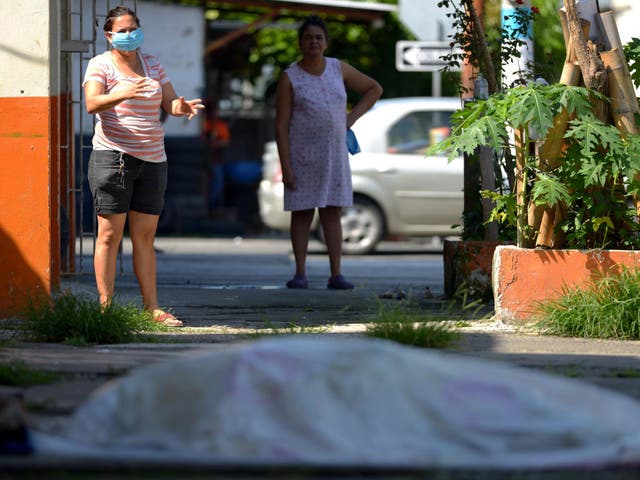 Women look at a body said to be laying outside a closed clinic for three days in Guayaquil on 3 April 2020