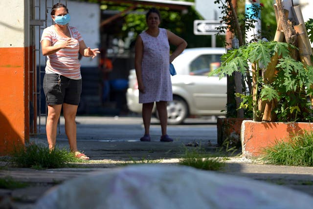 Women look at a body said to be laying outside a closed clinic for three days in Guayaquil on 3 April 2020