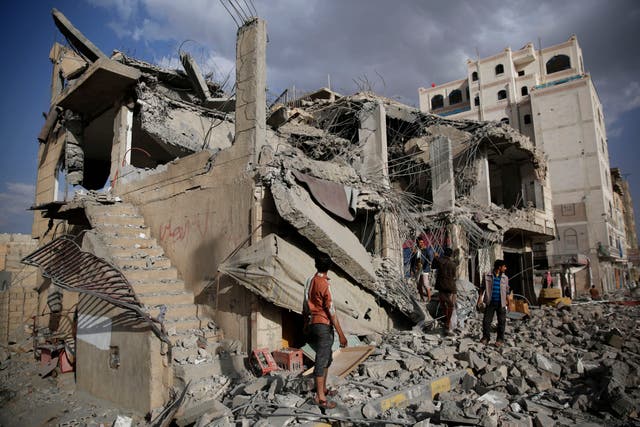 Men inspect a house destroyed by a Saudi-led airstrike in Sanaa, Yemen
