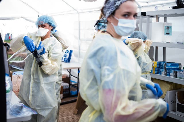 Medical workers put on personal protective equipment at the start of their shift at a field hospital run by Samaritan's Purse and Mount Sinai Health System in Central Park, New York, during the coronavirus pandemic