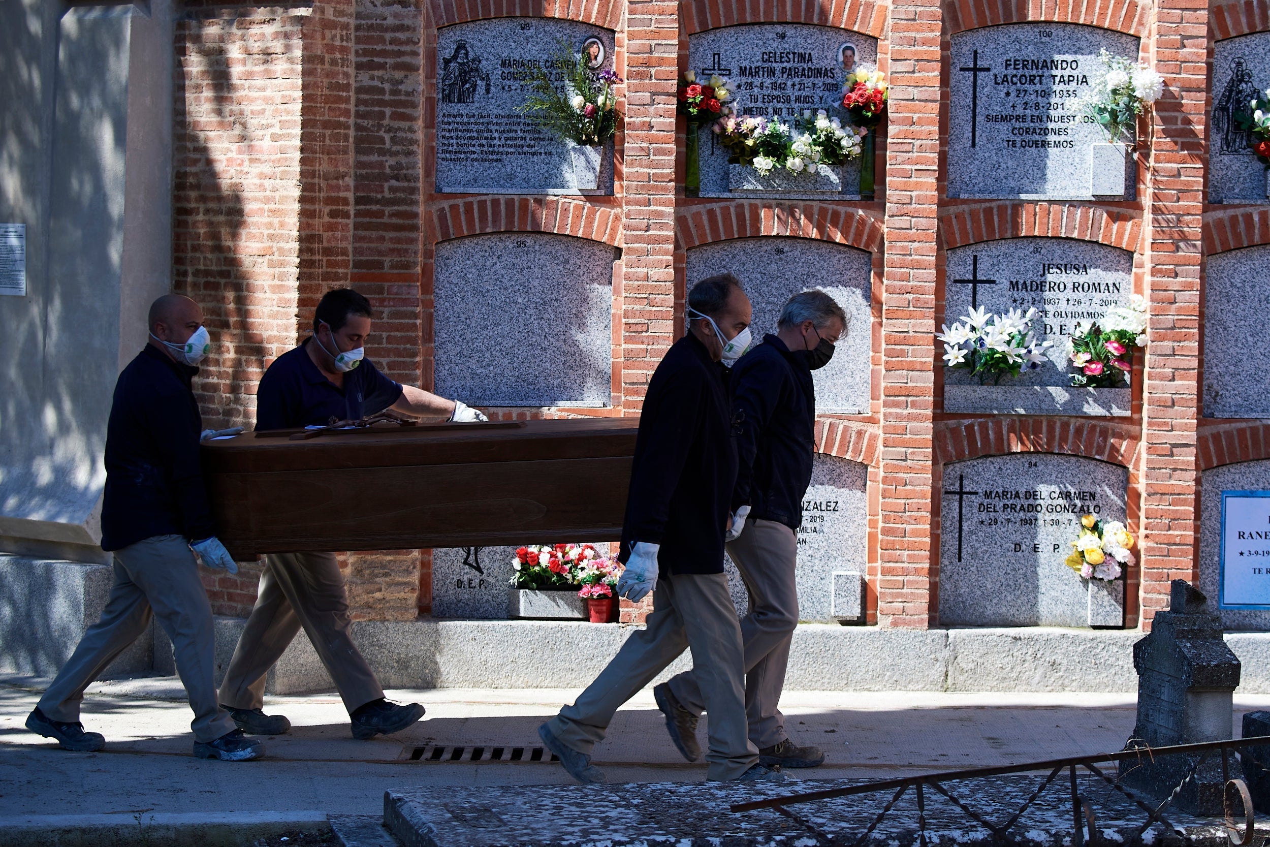 Mortuary employees transport a coffin of a Covid-19 victim at La Almudena cemetery in Madrid, Spain