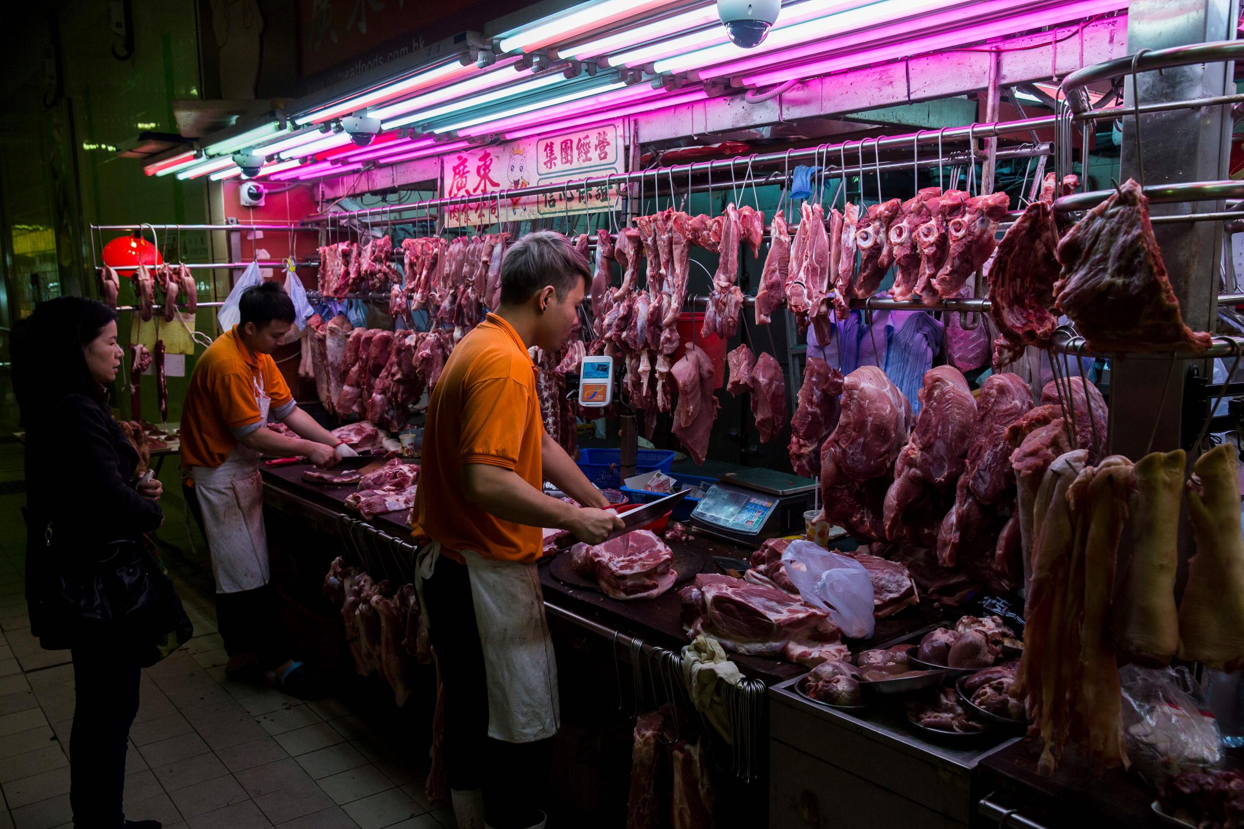 A stall worker cuts pork for a customer at the Wan Chai wet market in Hong Kong