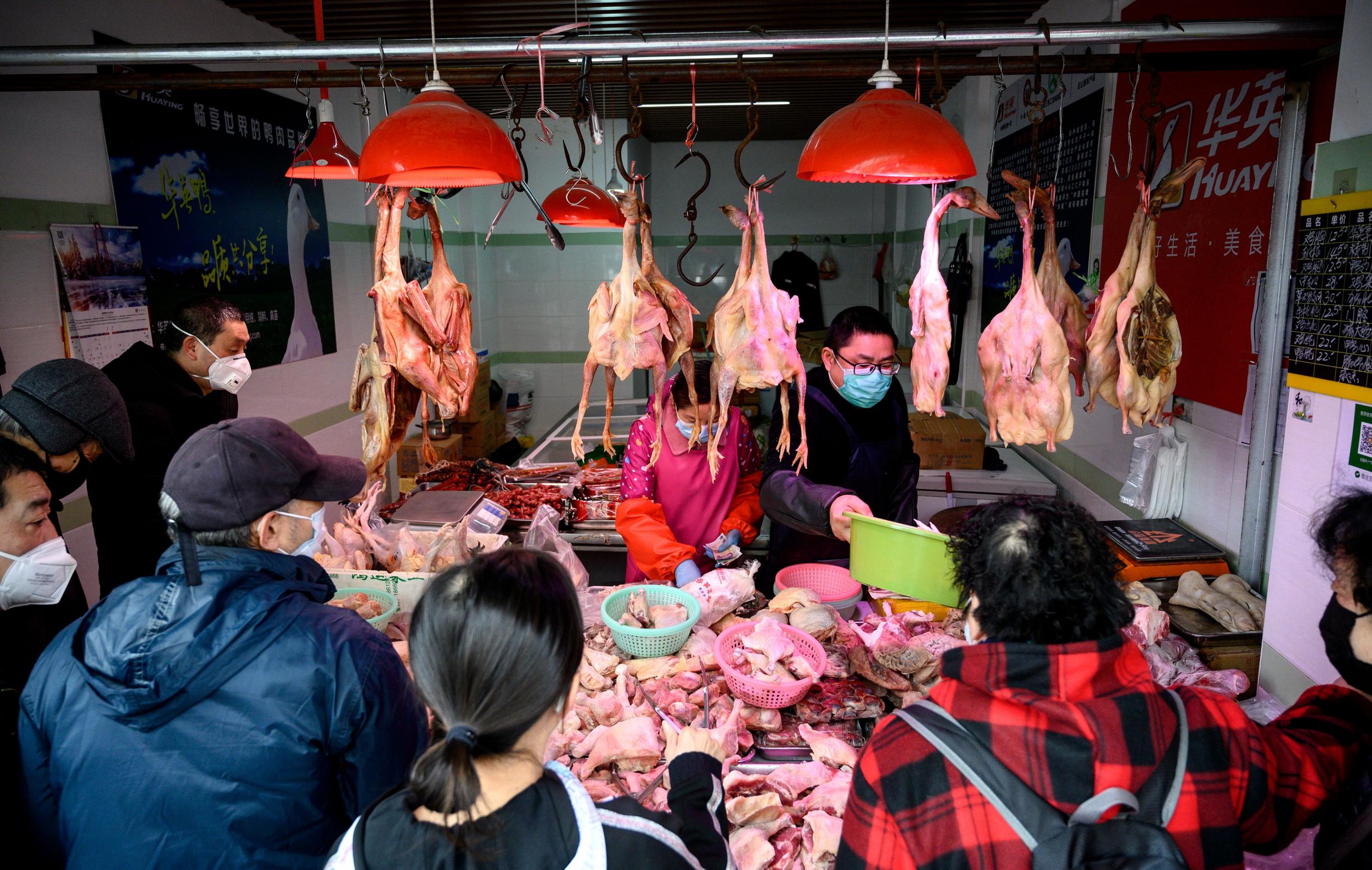 Customers and stall owners wear protective face masks shop at a chicken stall at a wet market in Shanghai