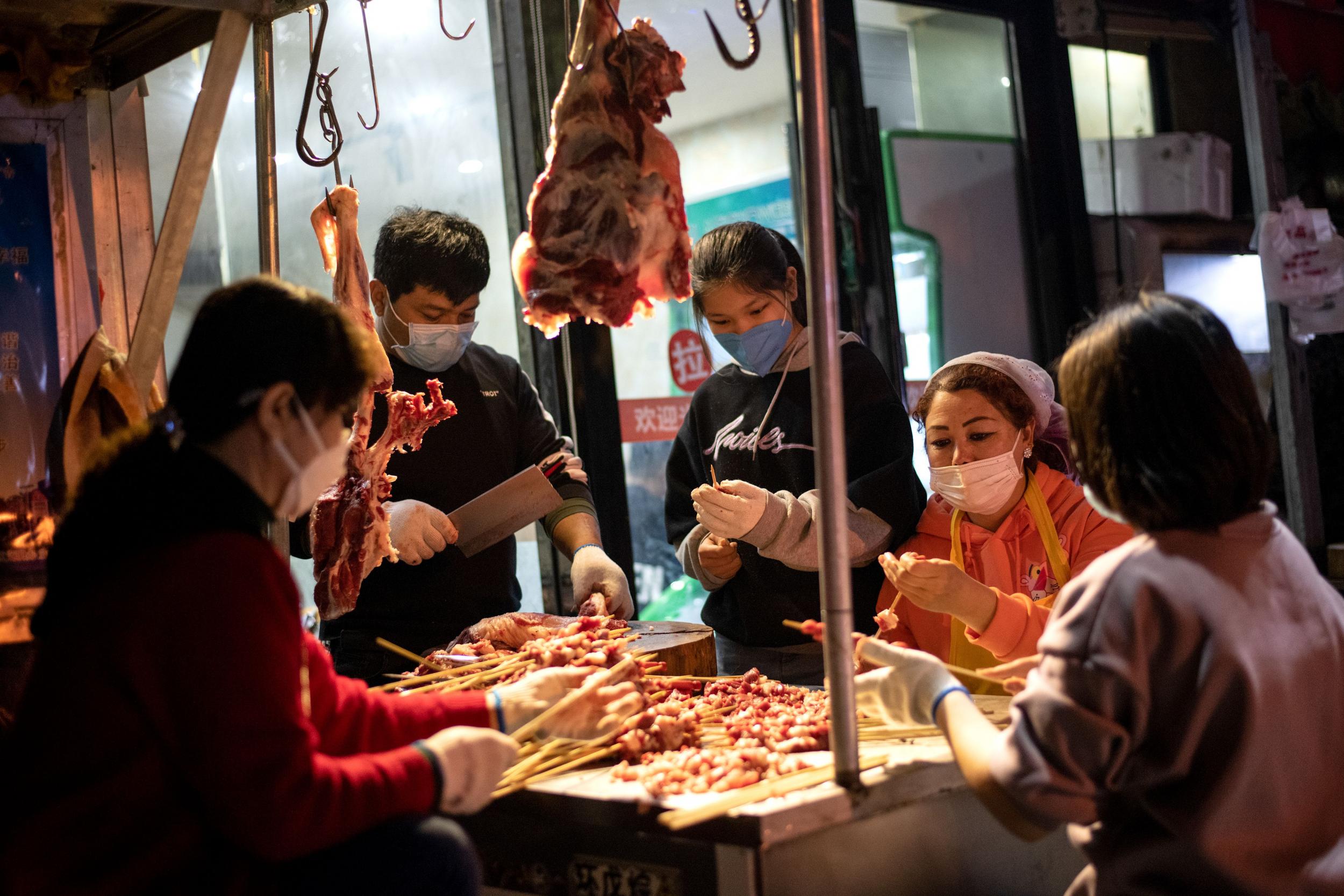 Workers wearing face masks prepare a barbecue at a market in Wuhan, China