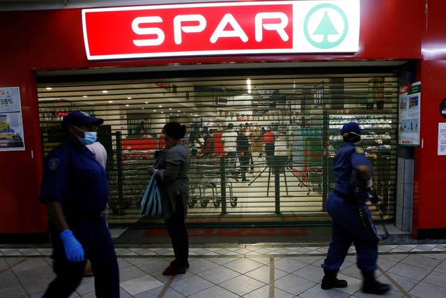 South African Police Service officers walk past shoppers queuing outside a shop in Sunnyside, Pretoria, 7 April 2020.